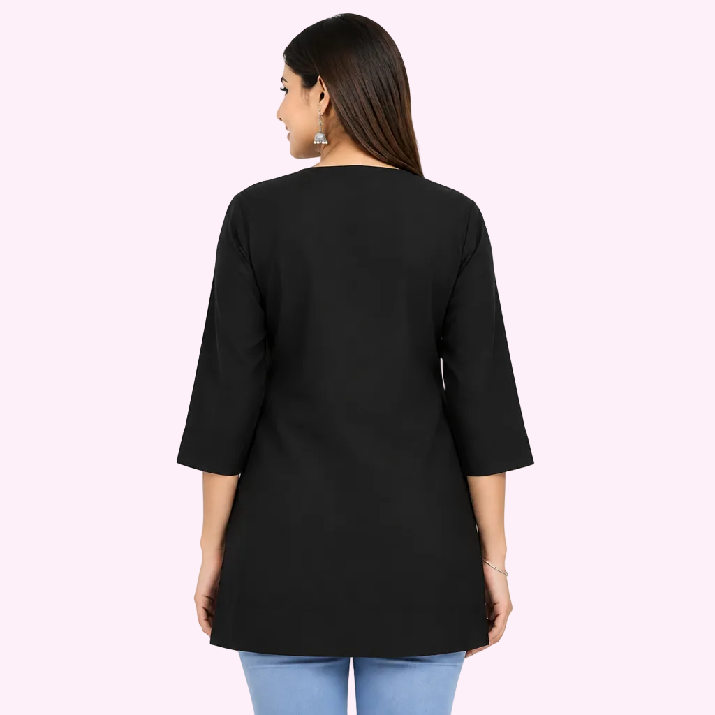 A woman shown from the back wearing a black three-quarter sleeve tunic top with a round neckline, paired with light blue jeans, against a plain white studio background.