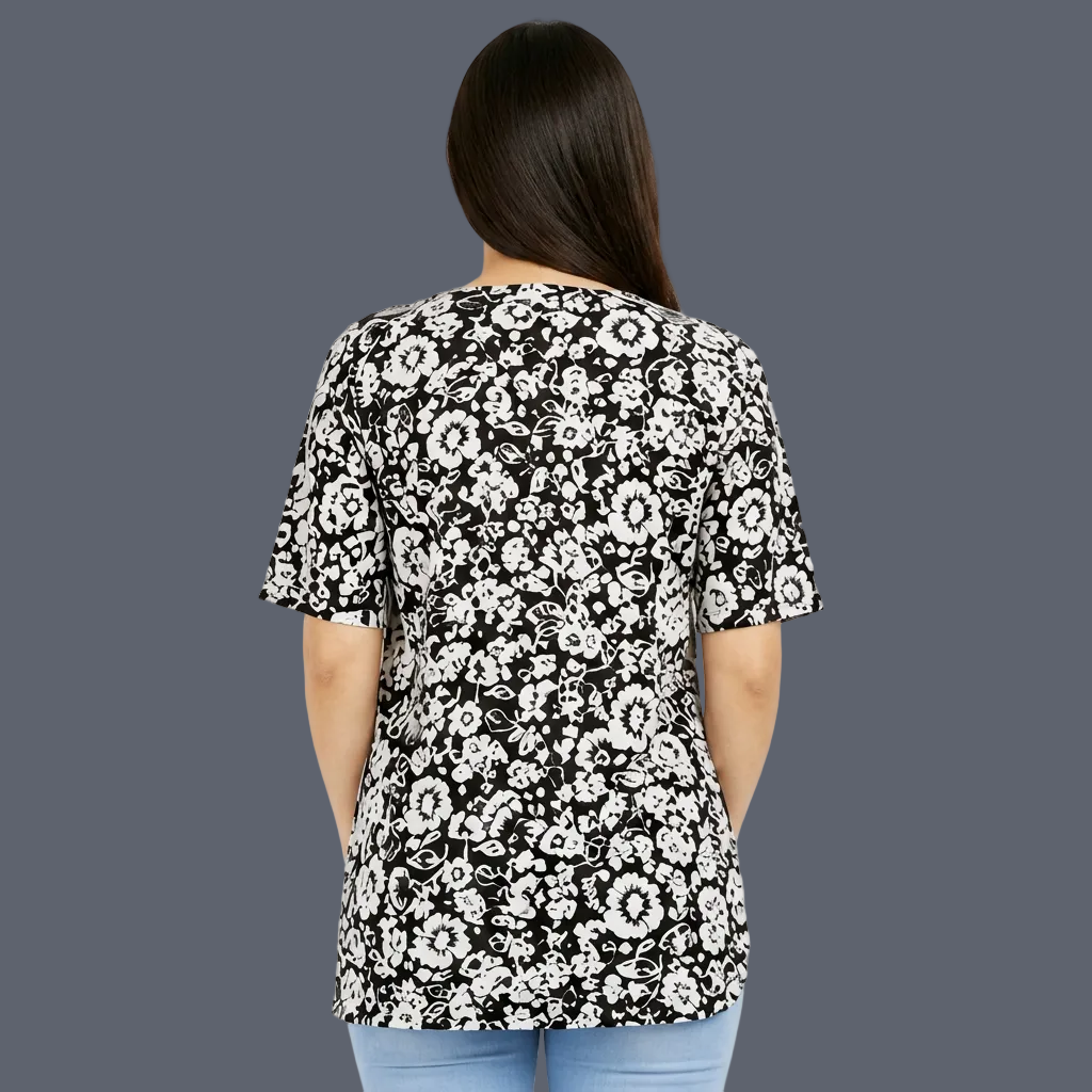 A woman shown from the back wearing a black short-sleeve top with a white floral pattern, paired with light blue jeans, against a plain light gray background.