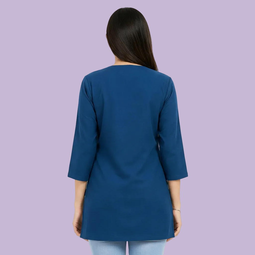 A woman shown from the back wearing a solid blue three-quarter sleeve tunic top, photographed against a plain light gray studio background.