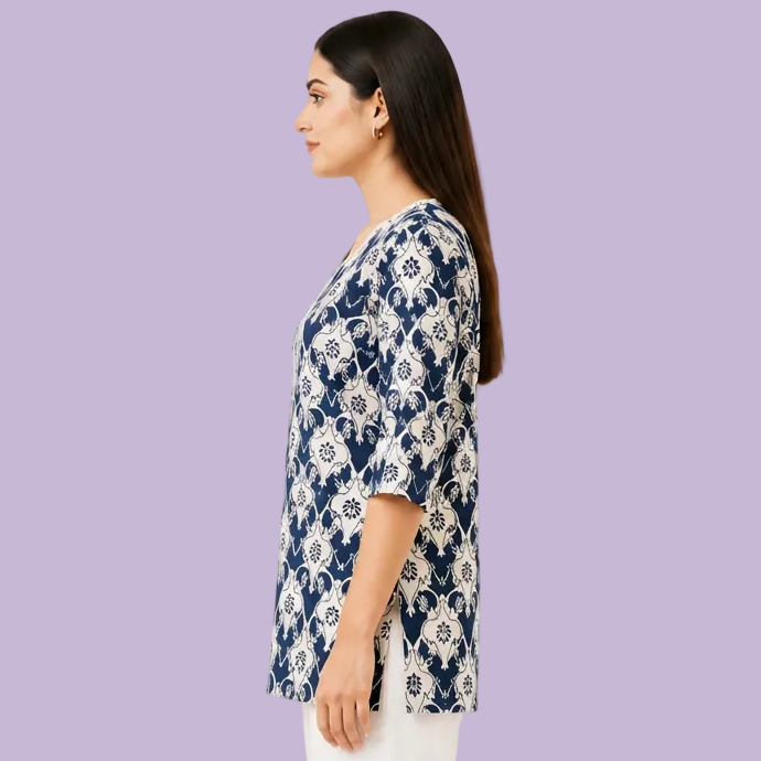 A woman shown in side profile wearing a navy and white floral print tunic top with three-quarter sleeves, paired with white pants, against a plain white background.