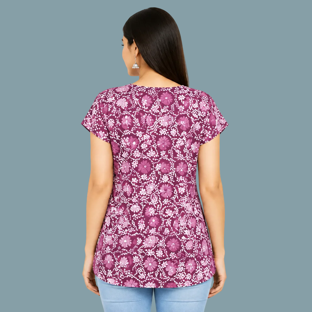 A woman wearing a short-sleeve purple and white floral printed kurta with a white lace V-neckline, paired with light blue jeans, set against a plain light gray background.