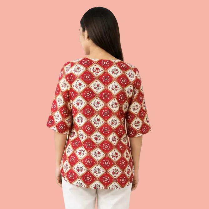 A woman viewed from the back wearing a red and cream patterned top with three-quarter sleeves and light-colored pants, set against a plain white background.